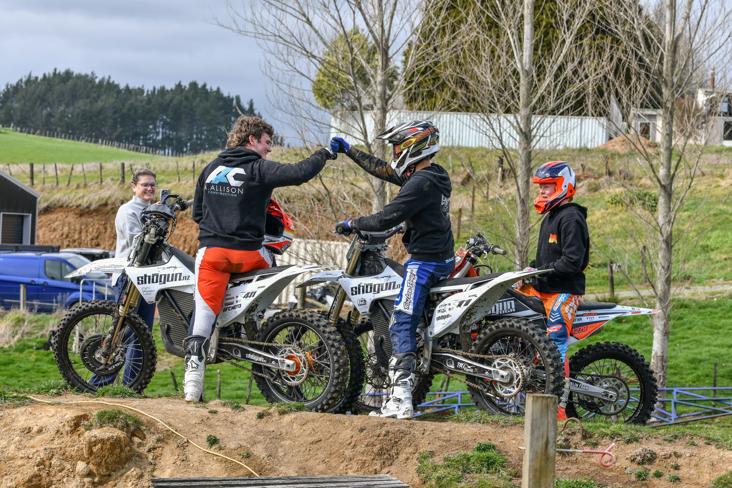 Motocross riders fist pumping and celebrating on dirt bikes after training session.
